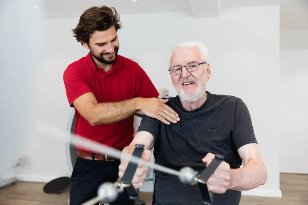 Ergotherapeut unterstützt einen älteren Patienten bei einer Bewegungsübung – PhysioVital Hamburg-Bramfeld